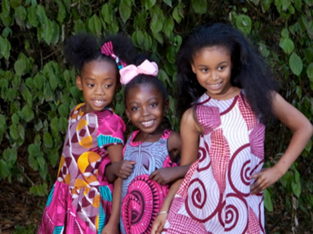 Three young girls wearing african printed dresses