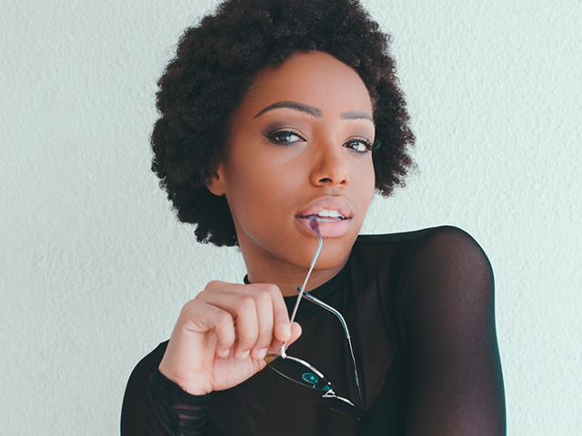 model with 4C hair holding sunglasses